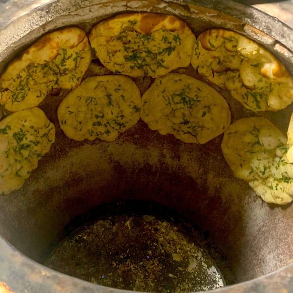 Naan bread baking inside a traditional tandoor oven at Taj Indian Cuisine.